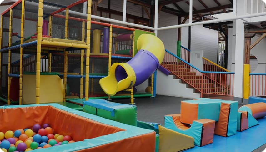 Parque infantil interior con estructuras de juego y piscina de bolas